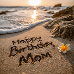 Happy Birthday Mom Written in Beach Sand with Ocean Foam Background, Warm Diffused Sunset and Tiny Ocean Flower Accent &ndash; perfect for birthday greetings