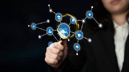A business professional uses a magnifying glass to analyze a digital network of icons, representing data insights and technology-driven growth within an innovative environment. Tessel