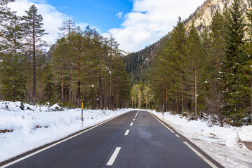 Deserted mountain road trhough a snowy evergreen forest on a winter day
