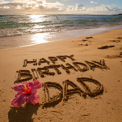 Happy Birthday Dad Written in Wet Sand Near Tide Line with Pink Hibiscus and Golden Sunset &ndash; perfect for birthday greetings