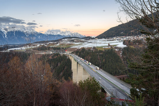 Traffic on a motorway bridge in the Alps at dusk in winter. Motion blurred. Tyrol. Austria.