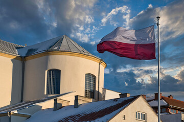 Polska flaga narodowa powiewająca na tle niebieskiego nieba. Symbol patriotyzmu, dumy narodowej i tożsamości polskiej. Idealne do ilustracji tematów związanych z Polską i świętami narodowymi.