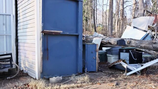 Vacant lot shows scattered debris, fallen trees, equipment among dry leaves branches in winter.