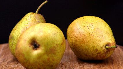 Fresh pears with water droplets on a rustic wooden surface.
