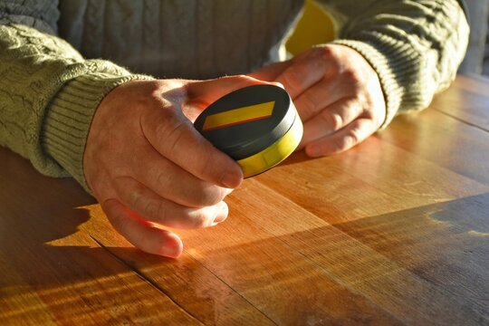 A man holds a box of snus. A box of snus pads replaces smokeless cigarettes. Swedish nicotine pouch.