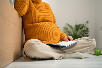 Close view of pregnant woman carefully compiling birth essentials list. Organized notes for maternity bag and important delivery reminders.