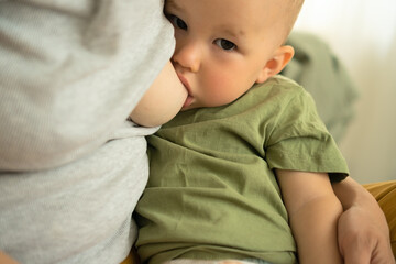 Content baby receiving mothers milk while sitting in loving arms. Intimate portrait of natural weaning and nutritional breastfeeding moment.