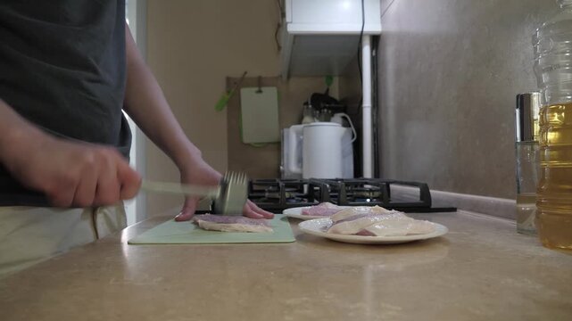 Preparing breakfast with fresh sliced pork, Person expertly cuts raw meat in cozy kitchen near stove in comfortable home environment