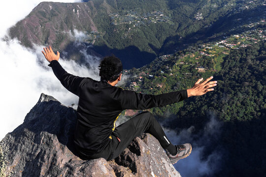 Young man practicing mindfulness on a mountain summit with open arms - Connection with nature. Hiker overlooking the lush green mountains and valley of El Avila National Park in Caracas, Venezuela