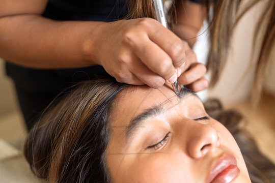 Beauty professional mapping client's eyebrows for shaping