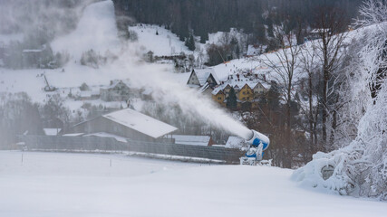 Snow cannon spraying artificial snow near mountain hotels in Poland
