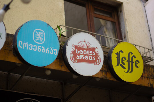 Tbilisi, Georgia - November 22, 2025: Street photo. Logo of German and Belgian beer brands on board signs with white heraldic lion, red star. Translation from Georgian: L&ouml;wenbr&auml;u, Stella Artois, Year