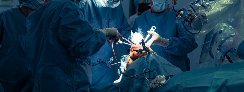 Surgeons work together in a bright operating room using a robotic surgical assistant to perform a knee replacement procedure, ensuring accuracy and safety throughout the process