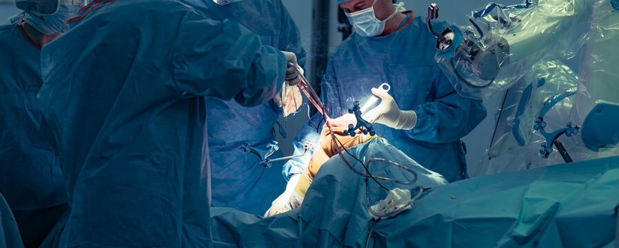 Surgeons employ a robotic surgical assistant during a knee replacement procedure, focusing on precise bone resections and soft tissue assessment - Powered by Adobe