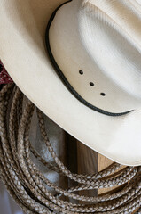 Closeup shows western gear, cowboy hat, rope rawhide lariat, and red bandana fabric.