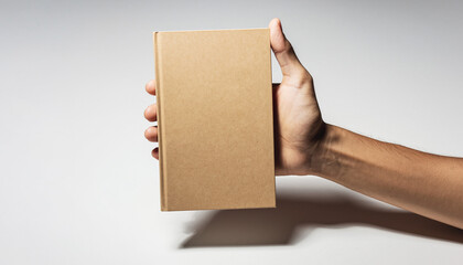 Hand holding blank brown cardboard box or book tightly