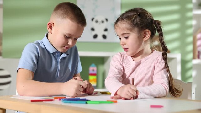 Children drawing with crayons at table indoors