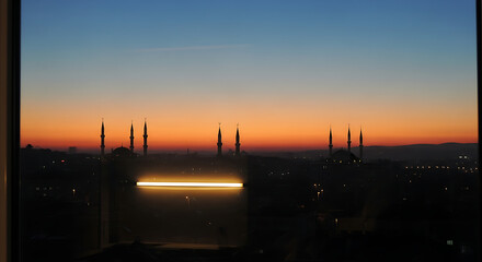 A serene cityscape at dusk with illuminated skyscrapers against a vibrant orange sky