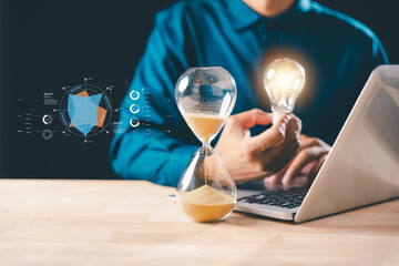 Hourglass time sand concept shows business lightbulb idea, professional works on laptop, managing countdown timer deadline for innovation and strategic planning