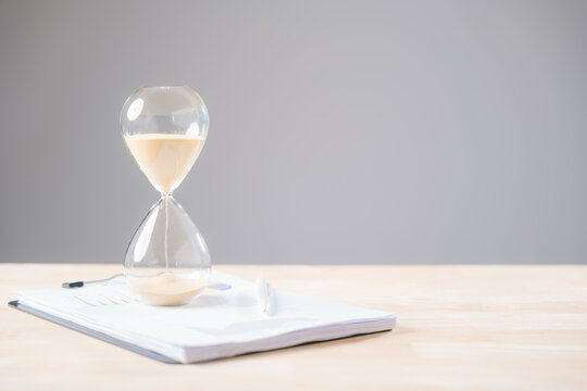 Hourglass showing passing time alongside important business paperwork, work documents, illustrating efficient time management and office tasks for successful business operations - Powered by Adobe