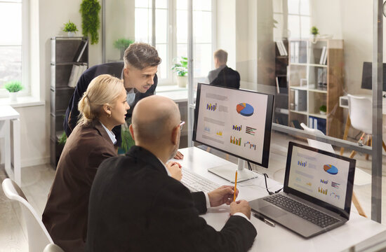 Businesswoman and businessman team meeting for analysis. Colleagues review data and charts on laptop and monitor in office, aligning strategy for a project. Clear office data analysis concept. - Powered by Adobe