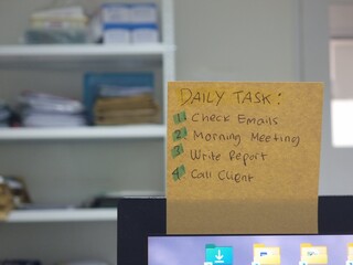 Sticky note daily tasks on computer monitor in office.