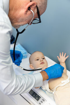 Doctor using stethoscope to listen on toddler boys tummy while lying dow n on a scale