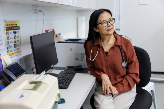 Female doctor sitting behind her desk inside exam room
