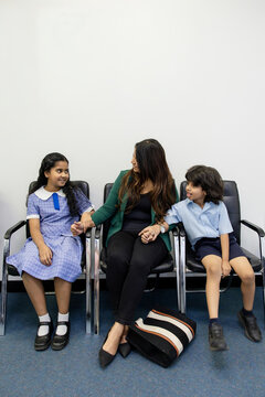 Mother with her two kids seated on waiting area of doctors clinic