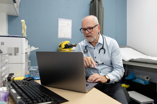 Doctor in office working at laptop