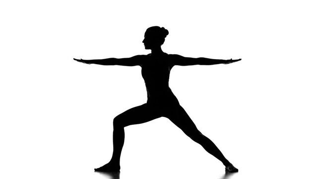 Woman silhouette practicing yoga warrior pose on a white background