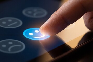 Finger pressing blue happy face button on touch screen to submit positive feedback and rating