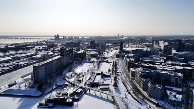 Aerial winter view of Montreal Old Port and frozen St Lawrence River with city skyline and harbor infrastructure. g.