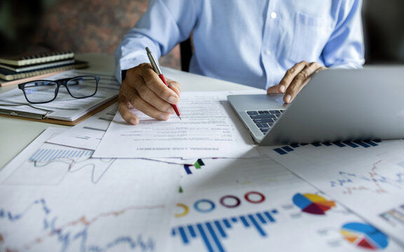 Investors working on desk with laptop checking financial report analyze investments and use data from charts to plan future investments - Powered by Adobe