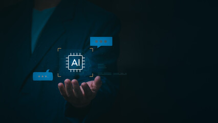 Businessman holding glowing AI chip icon with chat bubbles on dark background, Concept of artificial intelligence, machine learning, chatbot technology, digital transformation, and future innovation.
