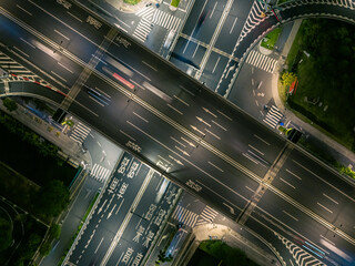 Aerial view of a busy highway intersection at night in an urban area, with moving car light trails. © Evgenii Bakhchev