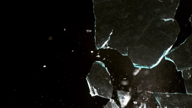 Real glass shattering and exploding in slow motion on black background