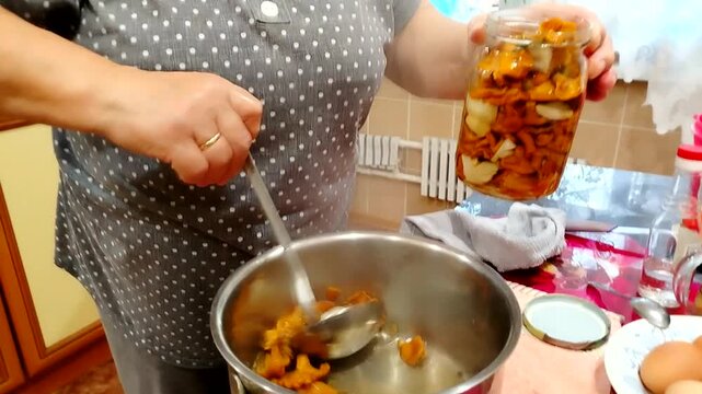 Video of home canning woman placing pickled mushrooms into a glass jar in the kitchen close up natural light face not shown perfect for b roll recipes, looping background