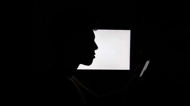 silhouette of a person using a phone at night, doomscrolling