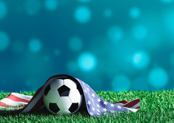 United States flag (USA) over a soccer ball on green grass in a stadium with a blue bokeh background.