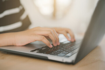 A close-up view shows a child&rsquo;s hands typing on a laptop keyboard, highlighting focus, technology use, and modern digital learning at home