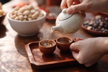Close up of person pouring hot tea into cups during traditional tea service