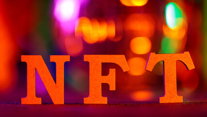 Wooden NFT Letters Standing on Dark Surface with Colorful Bokeh Lights Digital Economy Concept
