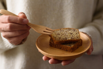 Delicious homemade banana bread or cake on rustic wooden plate holding by woman hand