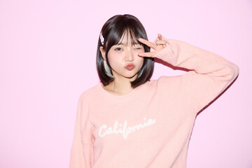 ピンク背景でキュートなポーズをする若い女性のポートレート