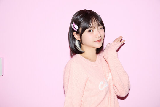 ピンク背景でキュートなポーズをする若い女性のポートレート