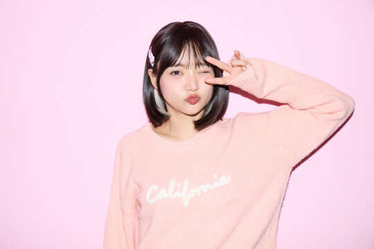 ピンク背景でキュートなポーズをする若い女性のポートレート