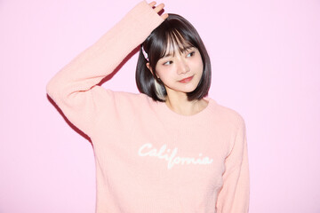 ピンク背景でキュートなポーズをする若い女性のポートレート