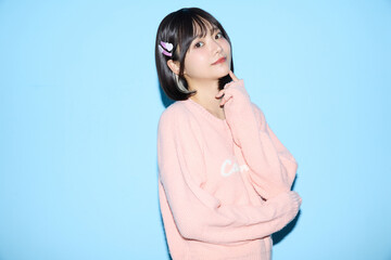 ブルー背景でキュートなポーズをする若い女性のポートレート