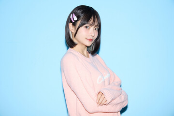 ブルー背景でキュートなポーズをする若い女性のポートレート